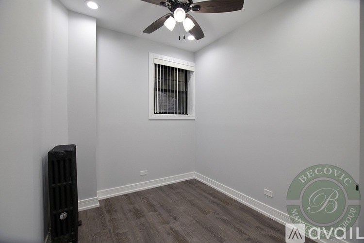 A room with a ceiling fan and a radiator on the wall.
