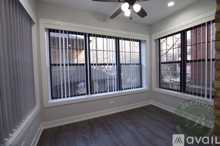 A room with a ceiling fan and two windows with blinds.
