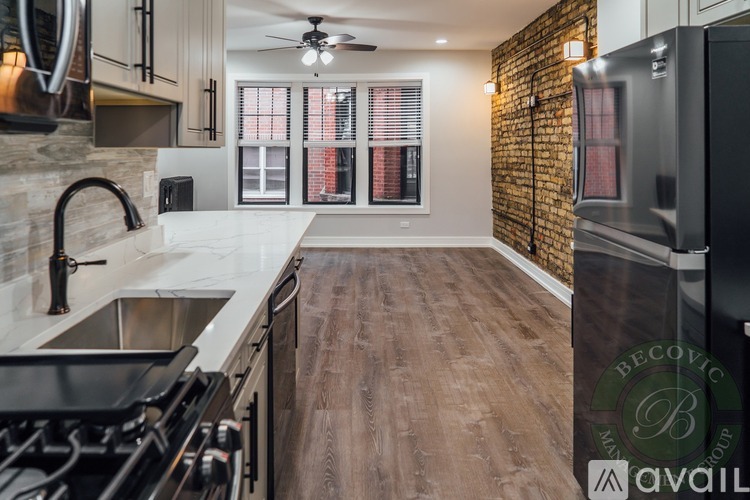 A kitchen with a brick wall and wooden floors.