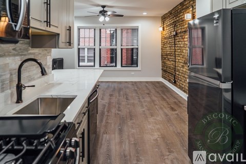 A kitchen with a brick wall and wooden floors.