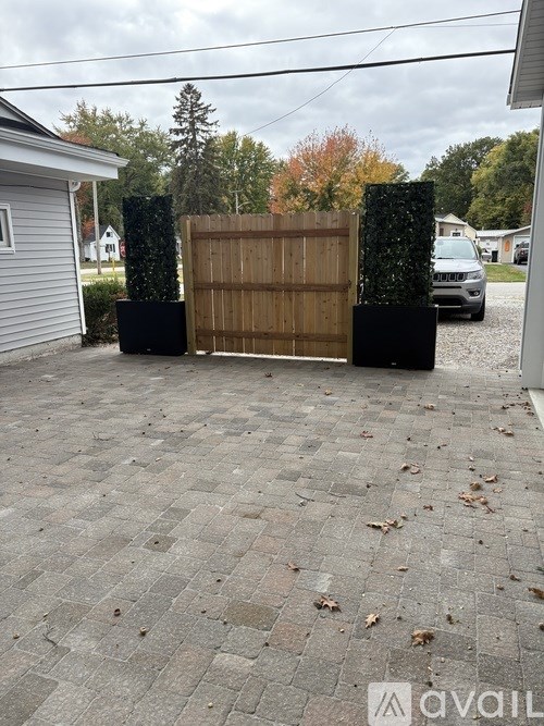 A wooden fence with a black metal gate is in front of a house.