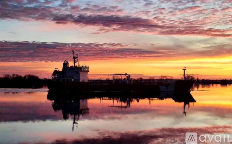 A ship is docked in a calm body of water during a beautiful sunset.