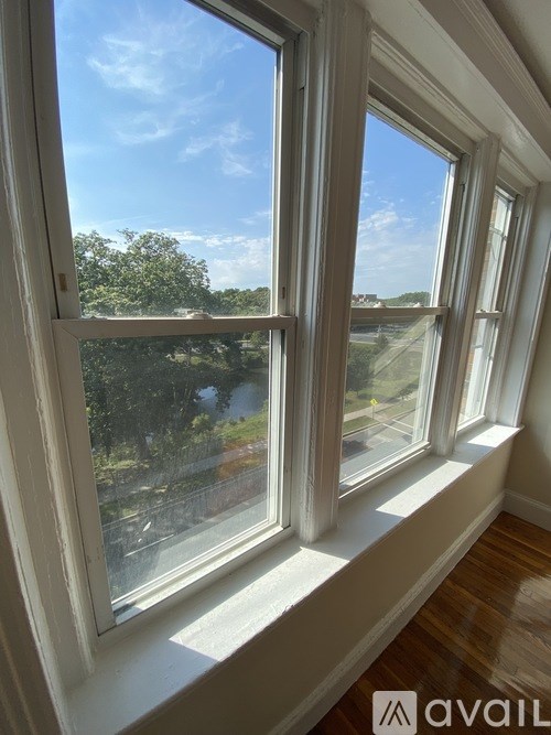 A window with a view of a street and trees outside.