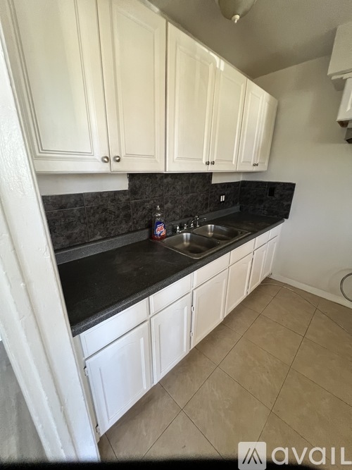 A kitchen with white cabinets and a black countertop.