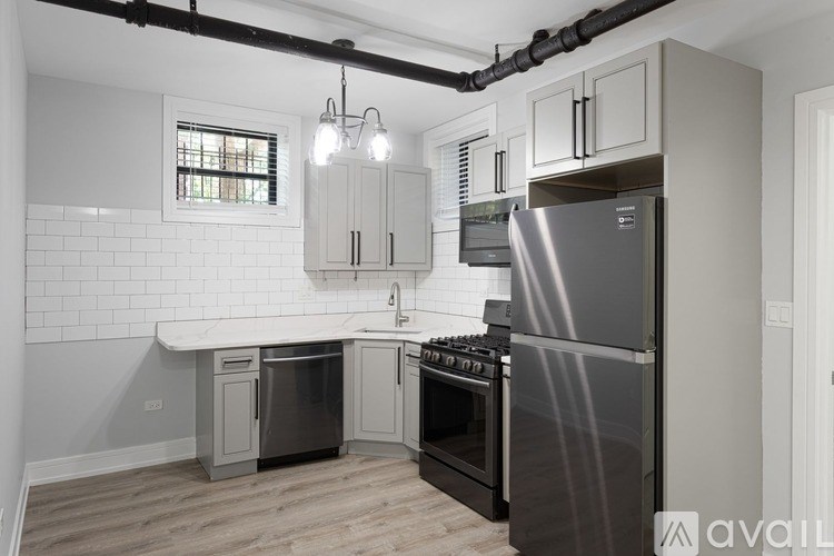 A modern kitchen with a stainless steel refrigerator and wooden flooring.