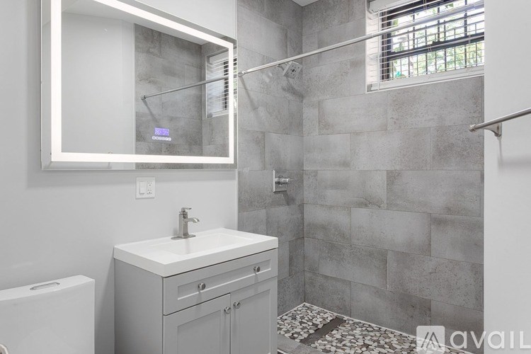 A bathroom with a white sink and grey cabinets.