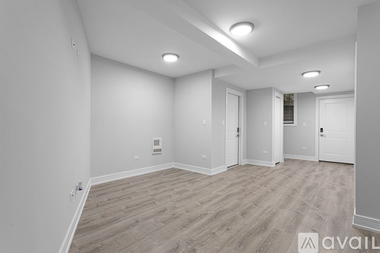 A spacious room with wooden flooring and white walls.