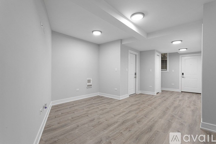 A spacious room with wooden flooring and white walls.