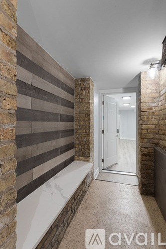A hallway with a brick wall and a white door.