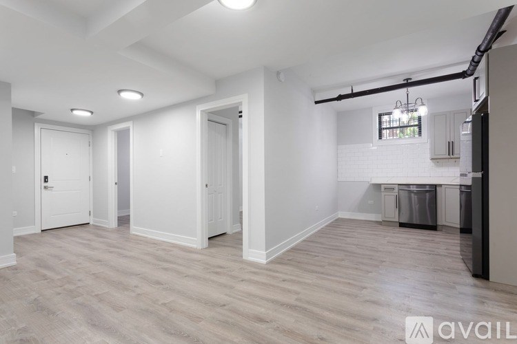 A spacious room with light wood flooring and white walls.