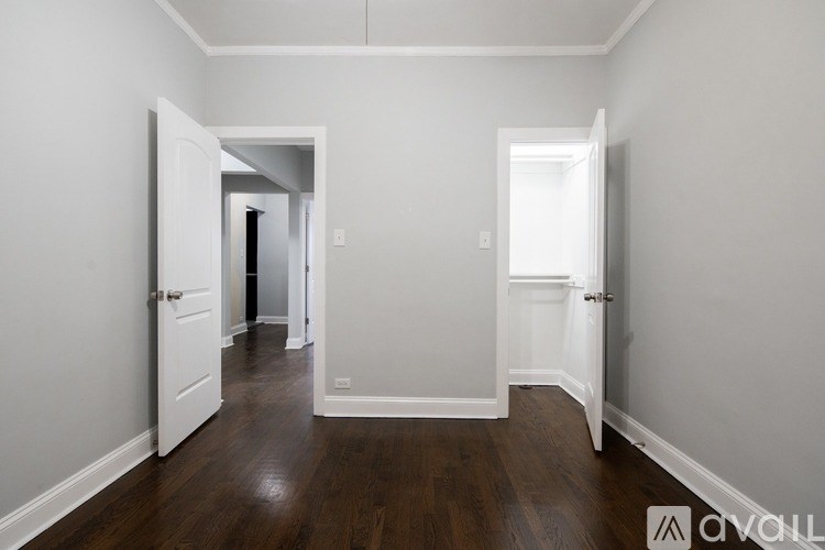 A hallway with white walls and wood floors.