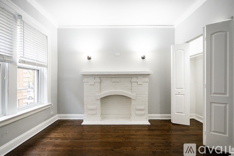 A white fireplace in a room with wooden floors and white walls.
