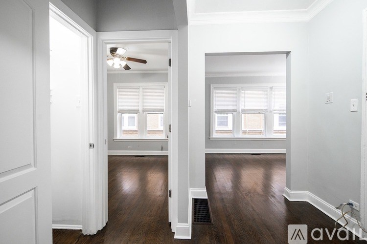 A spacious hallway with a ceiling fan and wooden floors.