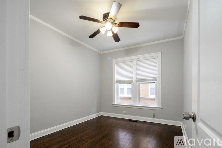 A room with a ceiling fan and a window with blinds.