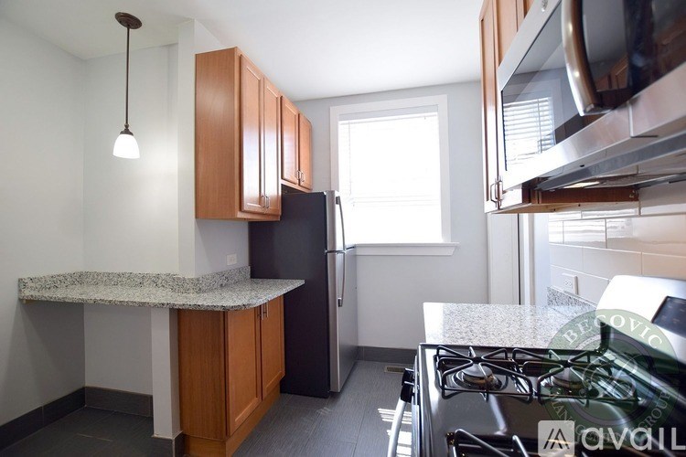 A kitchen with a granite countertop and a stainless steel refrigerator.