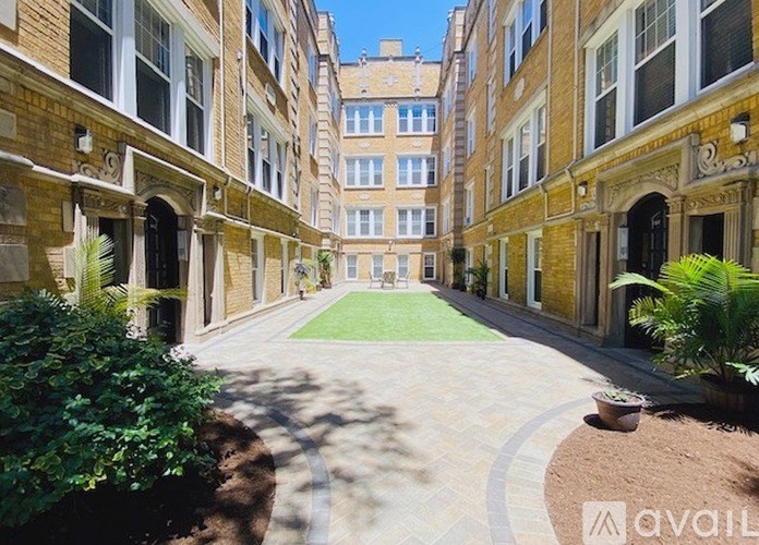 A courtyard with a brick pathway and a grassy area surrounded by buildings.