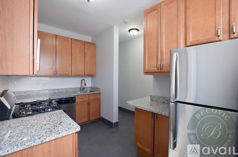 A kitchen with a refrigerator, cabinets, and a stove top.
