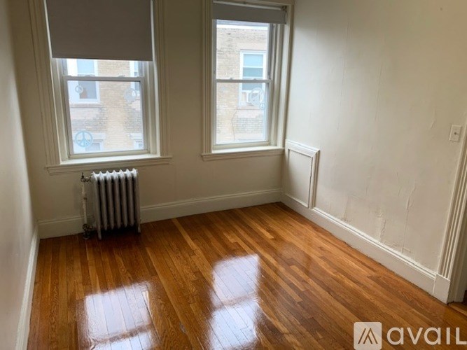 A room with wooden floors and two windows.