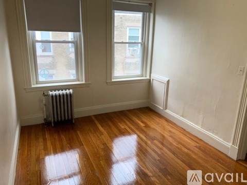 A room with wooden floors and two windows.