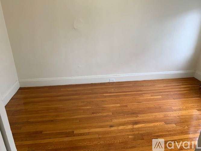 A room with wooden flooring and white walls.
