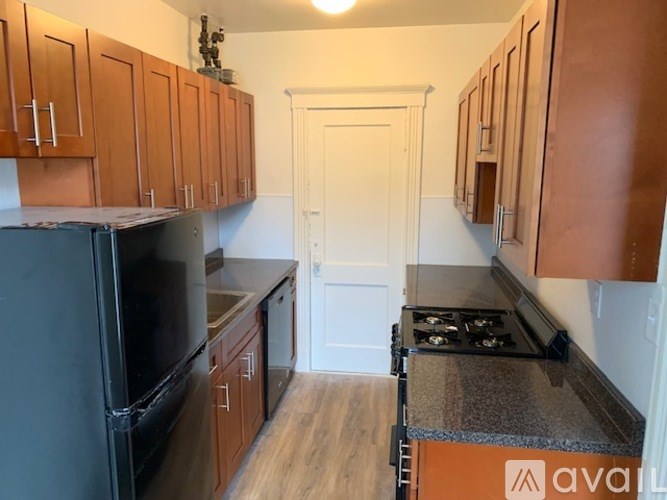 A kitchen with wooden cabinets and a black fridge.