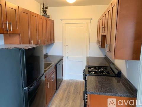 A kitchen with wooden cabinets and a black fridge.