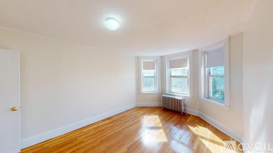 A room with wooden floors and three windows.