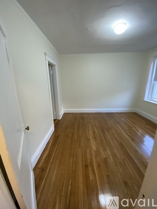 A room with wooden flooring and a doorway leading to another room.