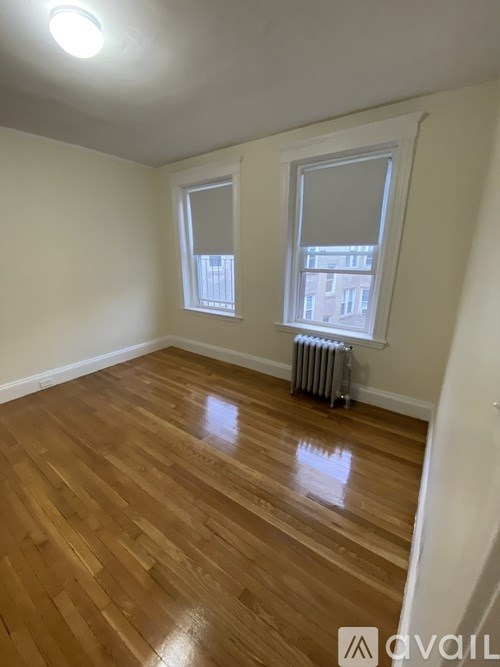 A room with wooden floors and a window with a view of a building outside.