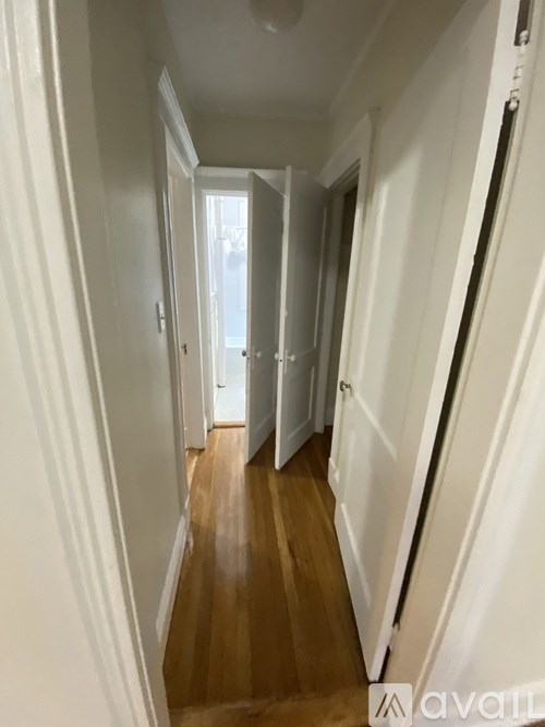 A long hallway with white walls and wood floors.