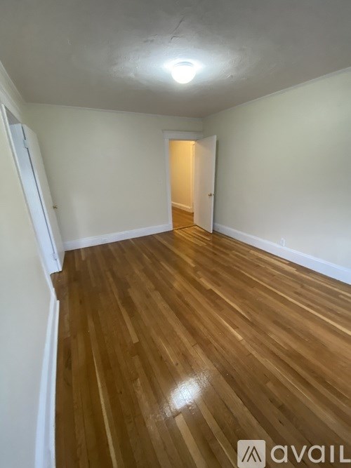 A room with wooden flooring and a doorway leading to another room.