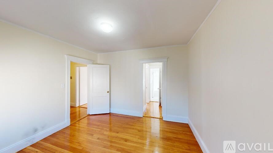 A room with wooden floors and white walls with two doors.