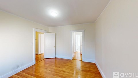 A room with wooden floors and white walls with two doors.