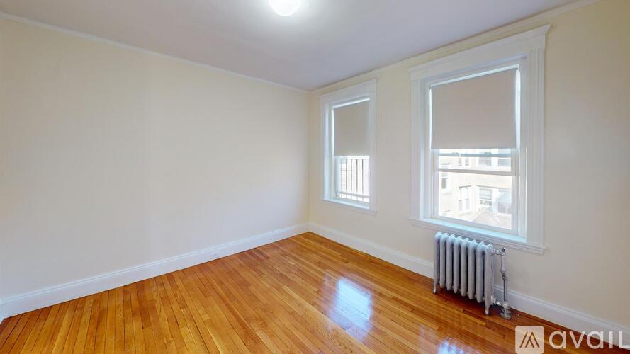 A room with wooden floors and a window with a view of a building outside.