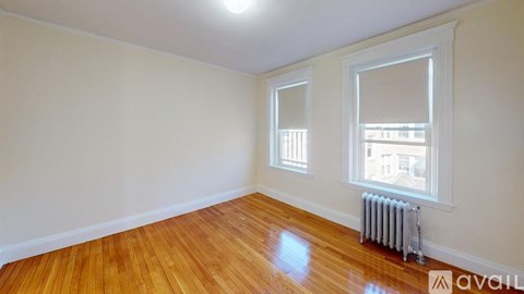 A room with wooden floors and a window with a view of a building outside.
