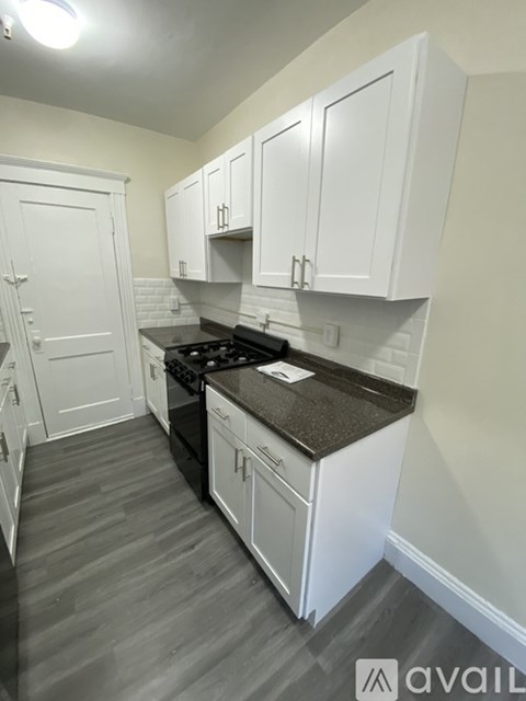 A kitchen with white cabinets and a black countertop.