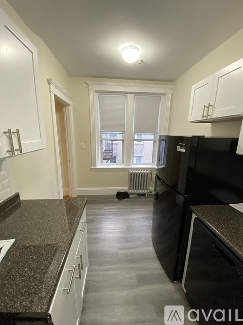A kitchen with black appliances and granite countertops.