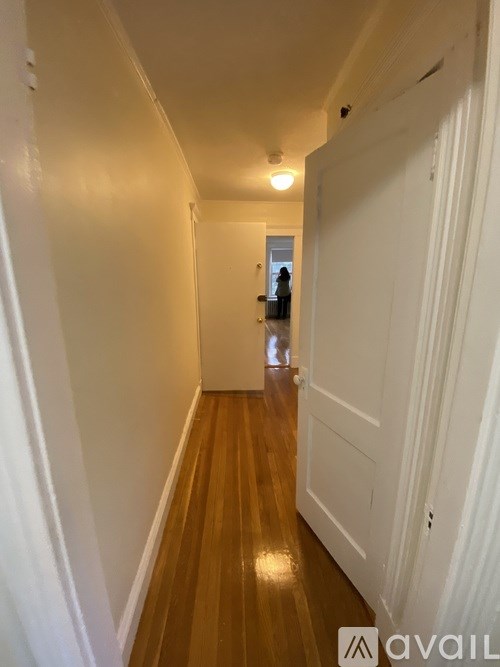 A hallway with wooden floors and white walls.