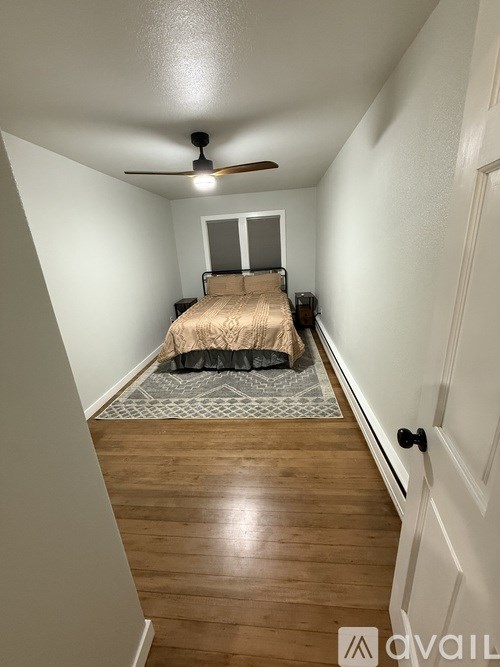 A bedroom with a bed, a ceiling fan, and a rug.
