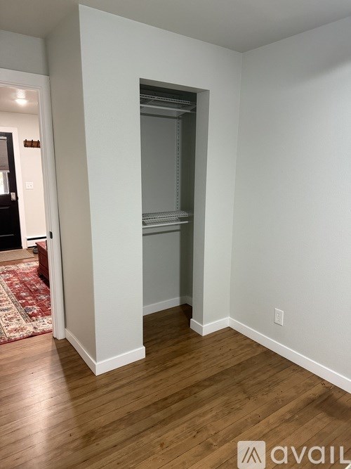 A room with a white wall and wooden floor.