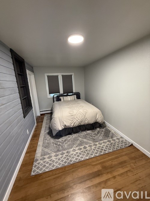 A bedroom with a bed, window, and wooden flooring.