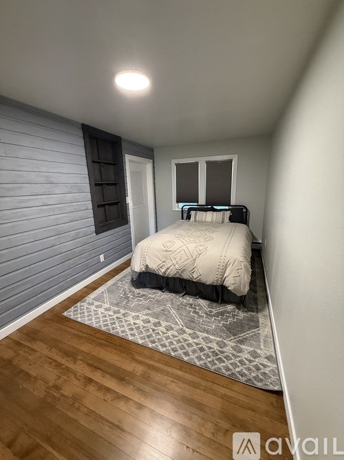 A bedroom with a bed, a window, and a wooden floor.