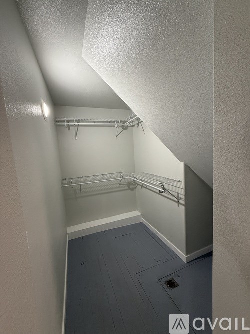 A small, empty room with a grey floor and white walls.