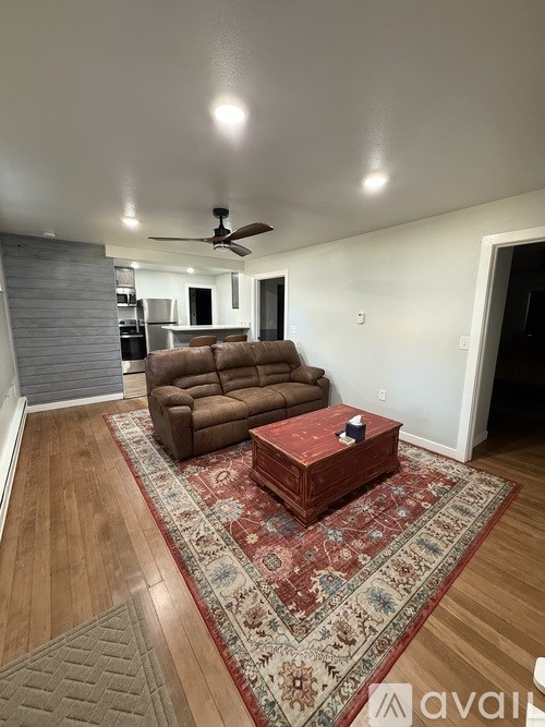 A living room with a brown couch and a rug.