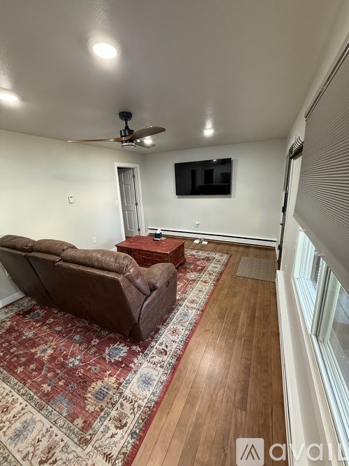 A living room with a brown couch and a rug.