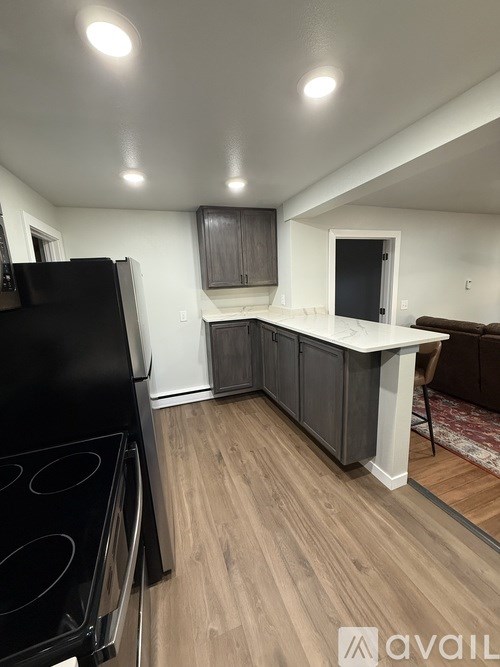 A kitchen with a black stove top oven and wooden flooring.