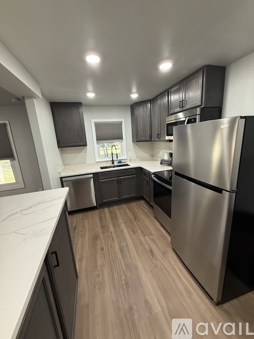A modern kitchen with a stainless steel refrigerator and wooden flooring.
