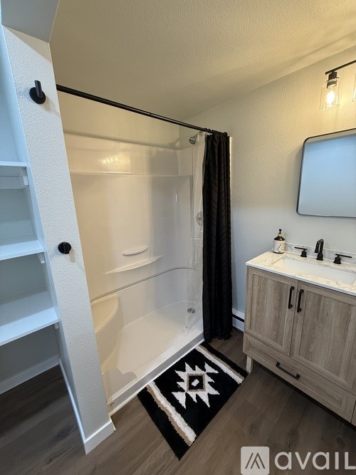 A bathroom with a white tub, sink, and a black and white rug.