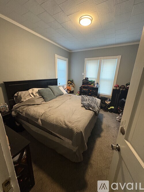 A bedroom with a bed, nightstand, and a window with blinds.