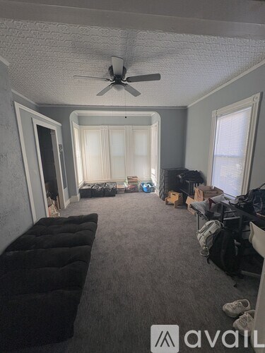 A room with a ceiling fan and a black couch.